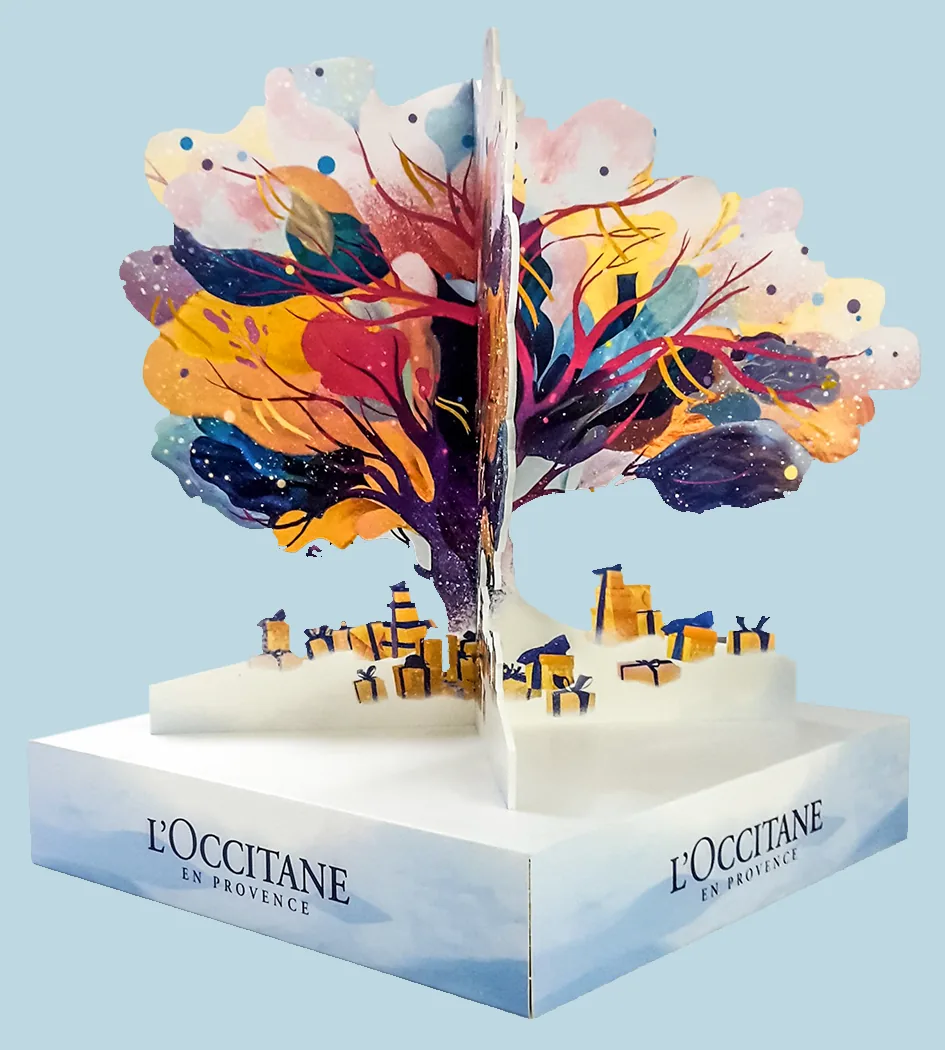 L'Occitane en Provence retail POS by City Images: hand-built display tree with painted-leaf canopy over a Provence-village plinth.