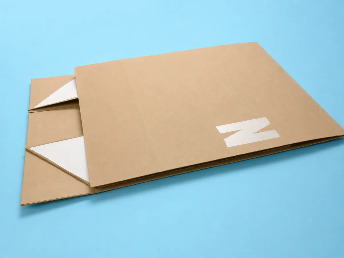 Kraft folding boxes shown flat-packed on a blue background, one partly assembled with white logo print