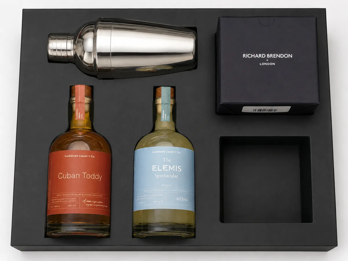 Black rigid box with fitted insert holding a cocktail shaker, two printed bottles and a branded glassware box