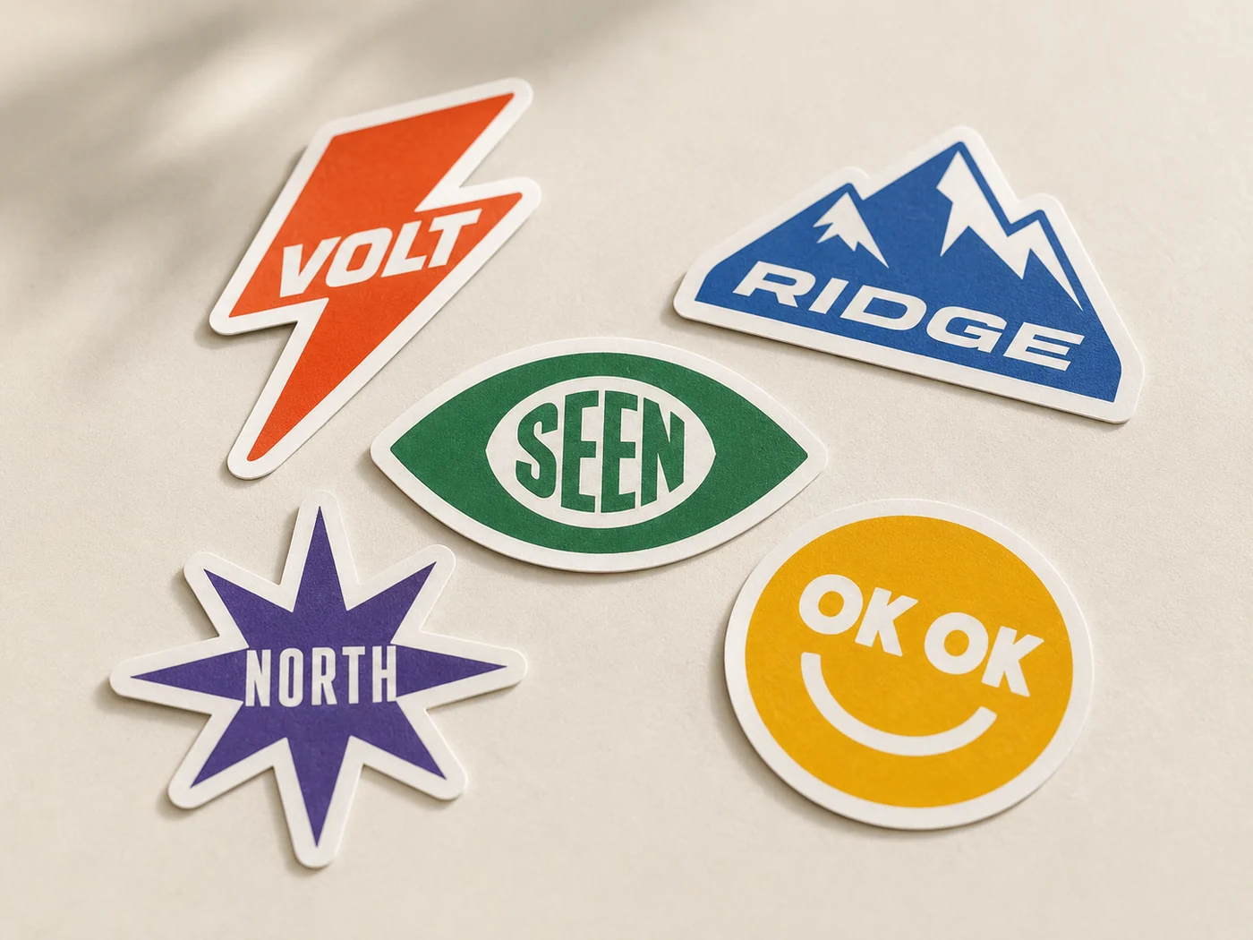 Die-cut vinyl logo stickers in assorted shapes and colours with tight white borders, a sticker sample