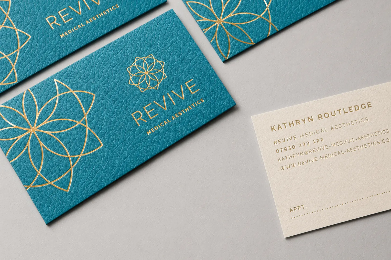 Gold foil business cards on teal stock with floral monogram, premium foil work