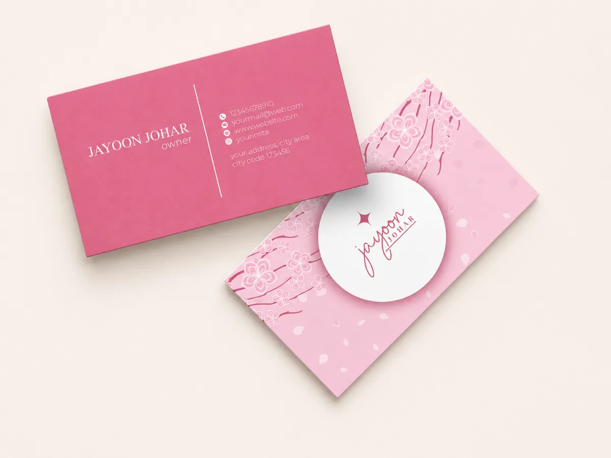Two pink business cards in magenta Colorplan with a printed confetti-pattern reverse and circular brand monogram