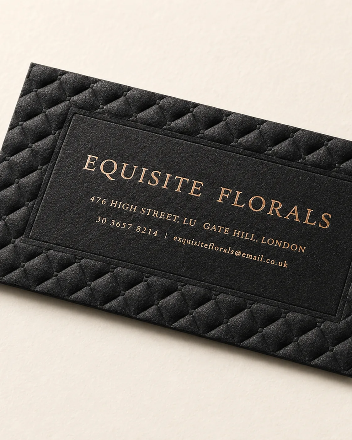Quilted-emboss black business card with digital-metallic gold typography on a soft-touch laminated surface