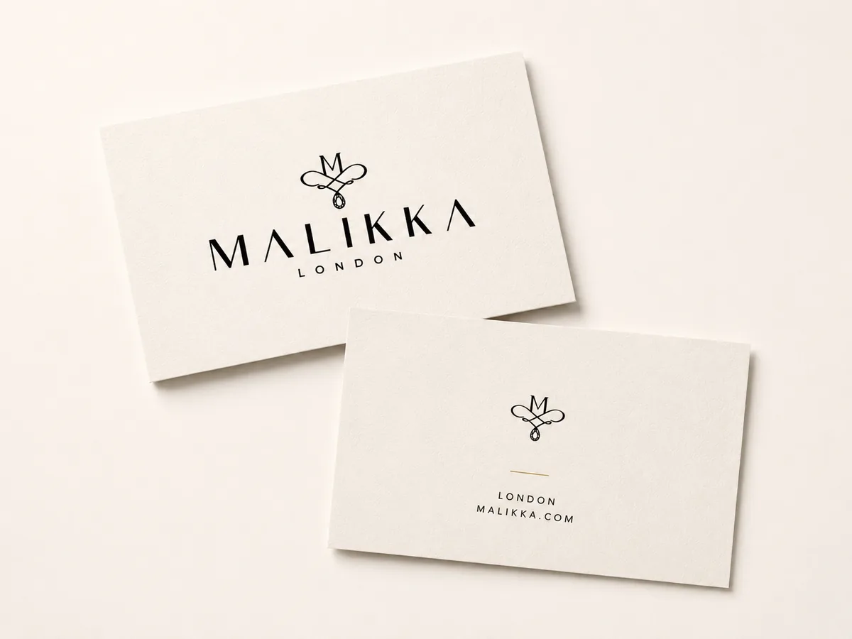 Two minimal cream Colorplan business cards with monogram and reverse on a neutral counter surface